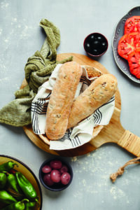 Filoncini alle olive serviti in un cestino, accompagnati da pomodori, peperoni e olive.