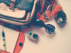 La borsa torna a fare la borsa Accessori da viaggio con borsa, taccuino, occhiali da sole, fotocamera e orologio disposti su un piano.