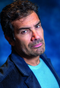 Primo piano di Marco Bonini su sfondo blu.