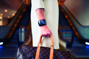Donna con abito chiaro porta una borsa Louis Vuitton in un ambiente moderno con scale mobili.